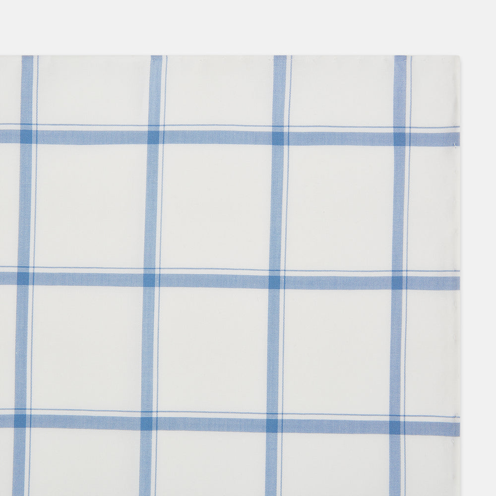 The Turnbull & Asser Colony Blue Grid Check Hand-Rolled Handkerchief features a white base with intersecting light and dark blue plaid lines forming squares, shown folded on a plain white background.