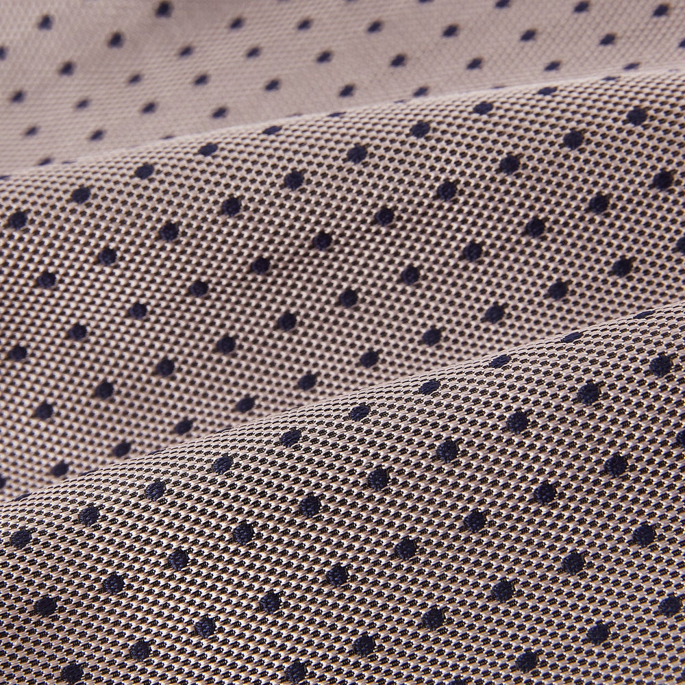 A folded, light-colored pocket square with small dark dots is displayed on a white background. Neatly arranged in a pointed fold, it pairs perfectly with the Turnbull & Asser Lilac and Navy Micro Dot Silk Cravat for an elegant look.