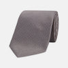 View 1 of product A close-up of the Dark Grey Plain Woven Lace Silk Tie by Turnbull & Asser, neatly rolled and textured, displayed on a light background—an elegant accessory for smart wardrobes.