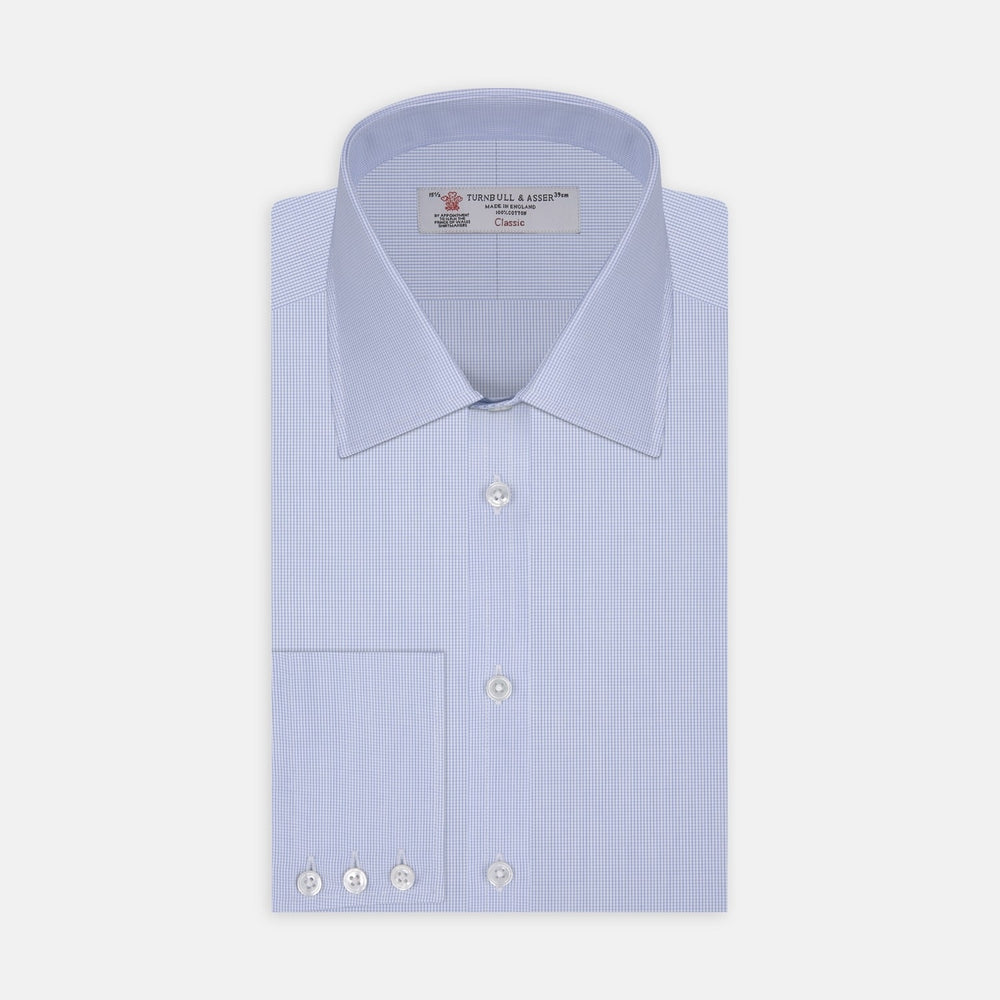 A circular swatch of Turnbull & Asser’s Light Blue Fine Check Cotton Fabric, featuring a fine vertical white grid on light blue, is bordered by a thin gray outline and shown against a plain white background.