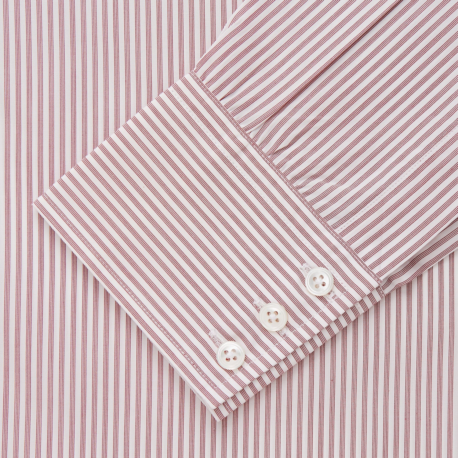 View 4 of product The Turnbull & Asser Burgundy Stripe West Indian Sea Island Cotton Regular Fit Mayfair Shirt features thin vertical red and white stripes, a classic collar, and long sleeves, shown on a plain white background.