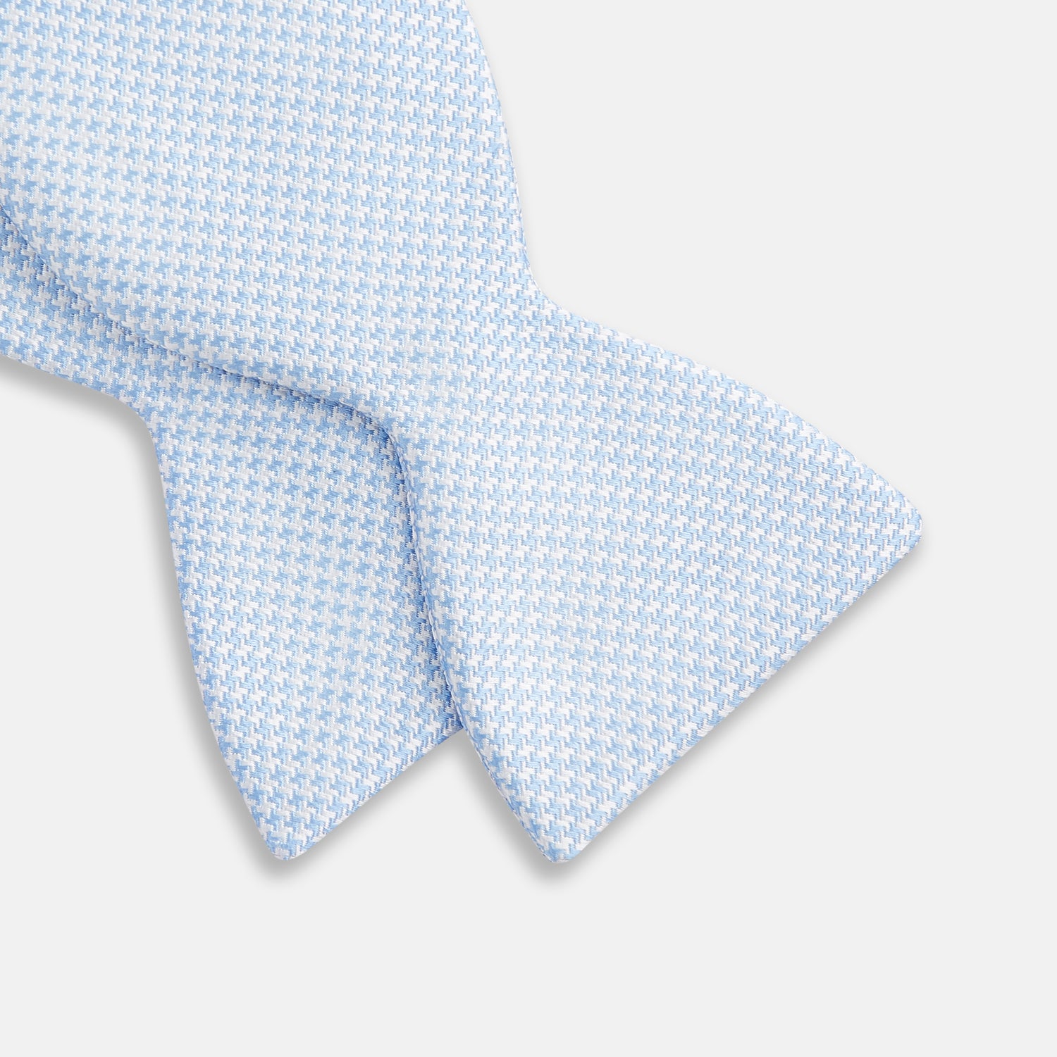 View 3 of product The Turnbull & Asser Pale Blue and White Houndstooth Silk Bow Tie features a refined textured pattern, making it an elegant formalwear accessory against a crisp white background.