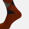 View 4 of product The Turnbull & Asser Rust Wool Check Mid-Length Sock features a brown wool design with black, gray, and orange checks, shown on a white background.