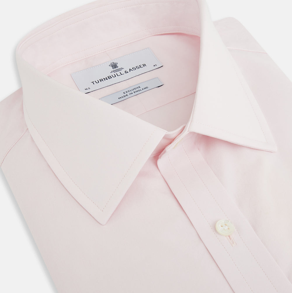 The Soft Pink Mayfair Shirt by Turnbull & Asser is a long-sleeved, sanforised cotton button-up with a classic collar, white buttons, and buttoned cuffs, shown against a plain white background.