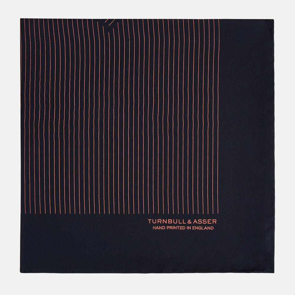 The Navy and Orange Stripe Silk Pocket Square by Turnbull & Asser is handmade in England from silk, featuring thin orange geometric stripes on navy and "Turnbull & Asser Hand Printed in England" printed in the corner.