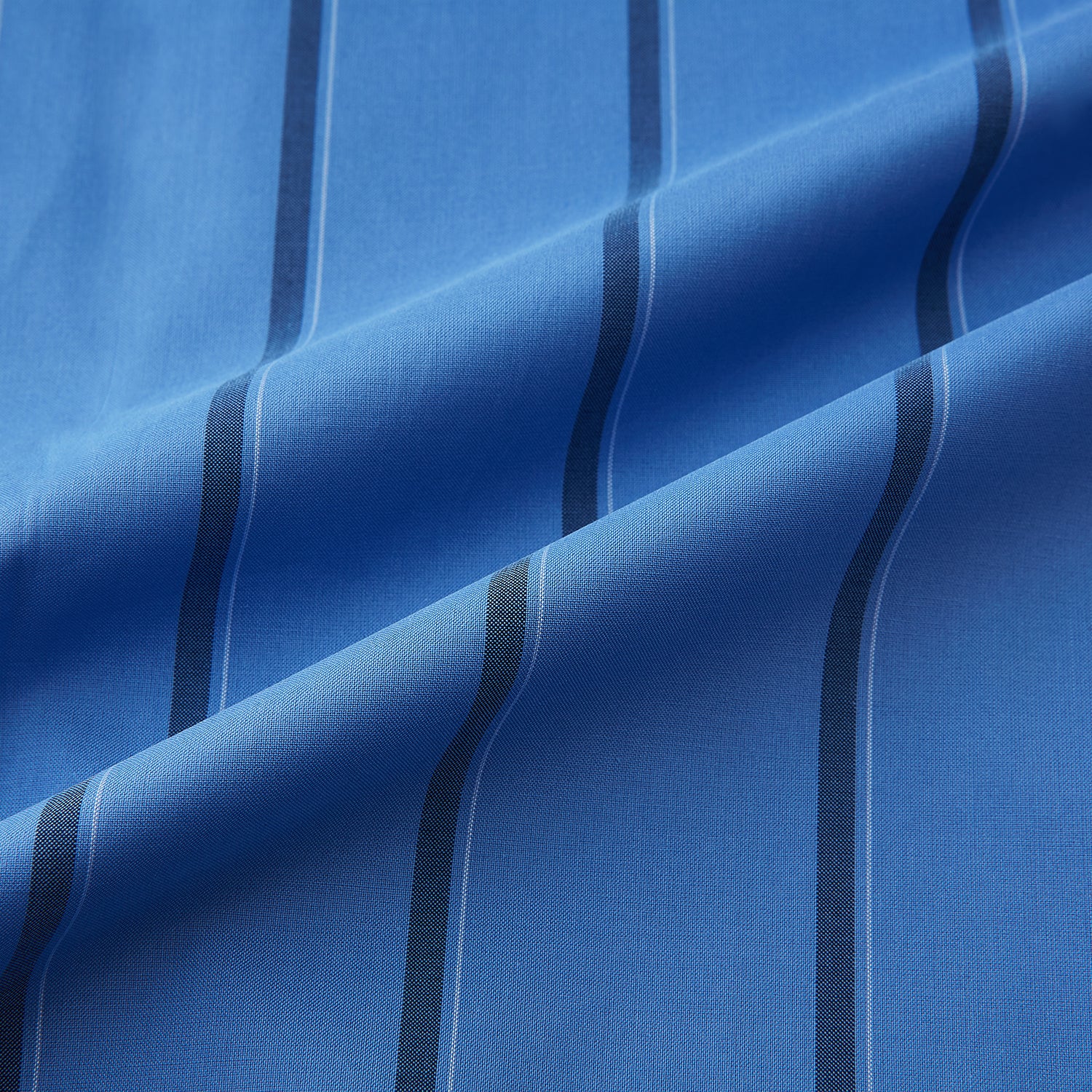 View 6 of product The Turnbull & Asser Colony Blue Track Stripe Mayfair Shirt is crafted from Italian cotton with long sleeves, dark blue track stripes, a classic collar, and buttoned cuffs, shown against a white background.