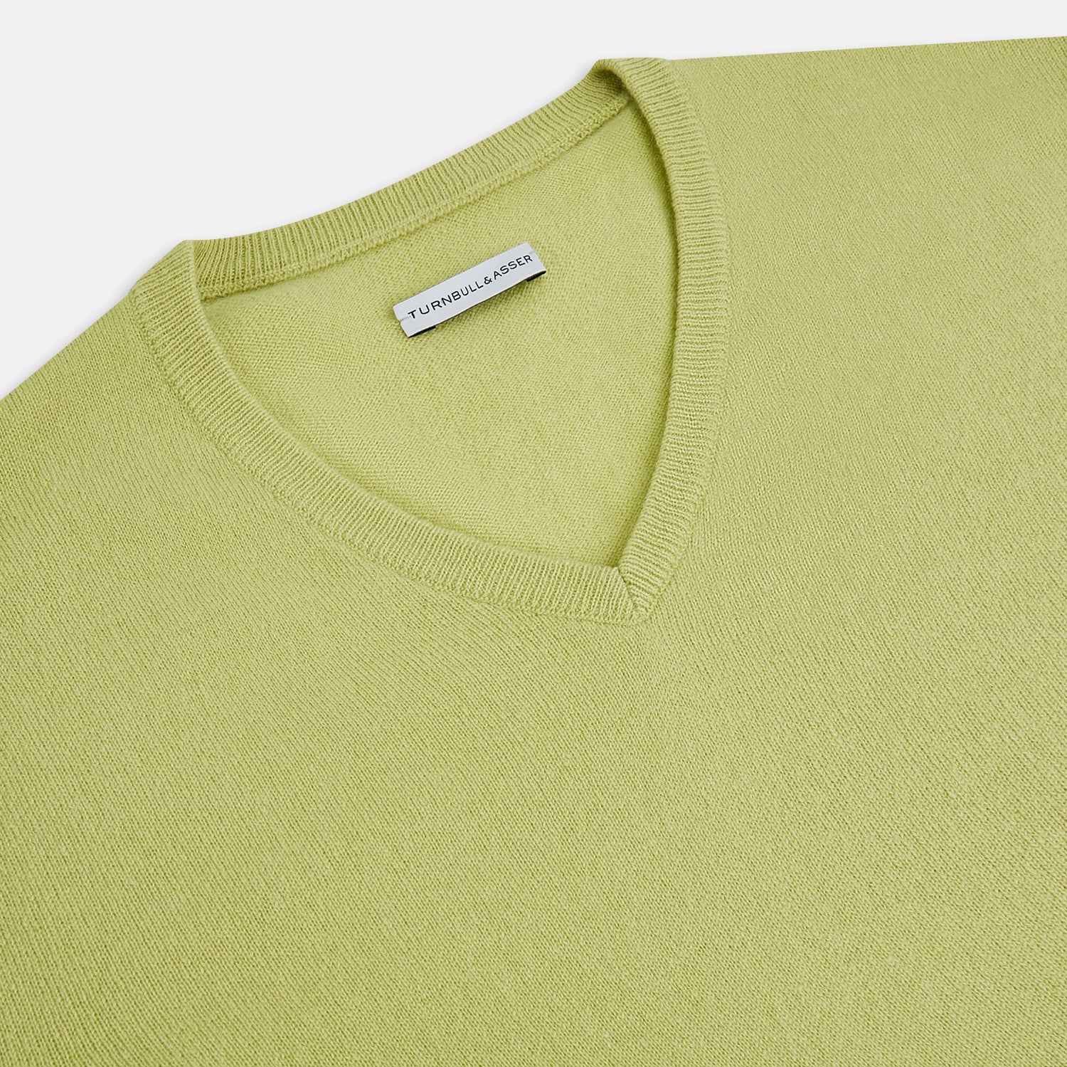 View 2 of product The Turnbull & Asser Melon Green Cashmere V-Neck Jumper features long sleeves with ribbed cuffs and hem, shown against a plain white background.