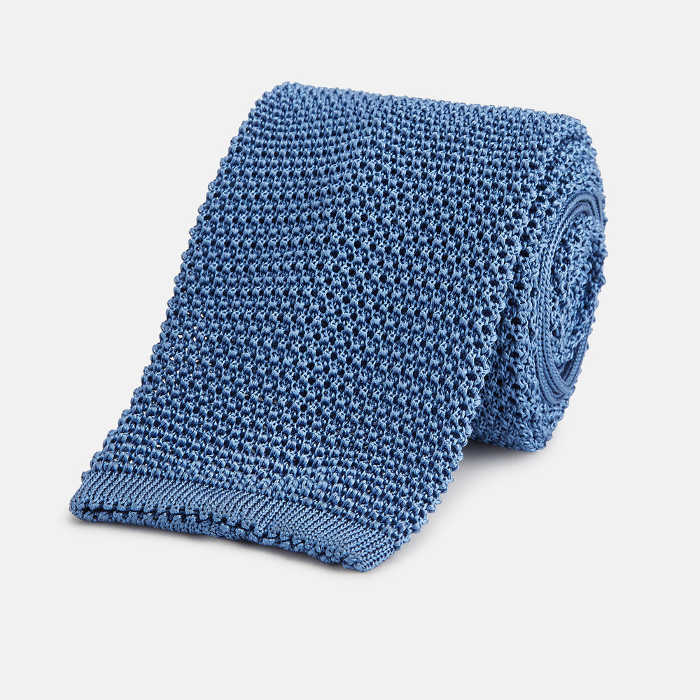 The Turnbull & Asser Knitted Mid Blue Silk Plain Tie features a textured knit and is shown rolled up on a plain white background—a refined accessory that pairs perfectly with formal shirts.
