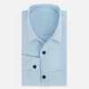 View 5 of product The Blue Hyde Overshirt by Turnbull & Asser features a light blue hue, long sleeves, a button-up front, and a single chest pocket. Crafted from sanforised cotton and shown laid flat on a white background.