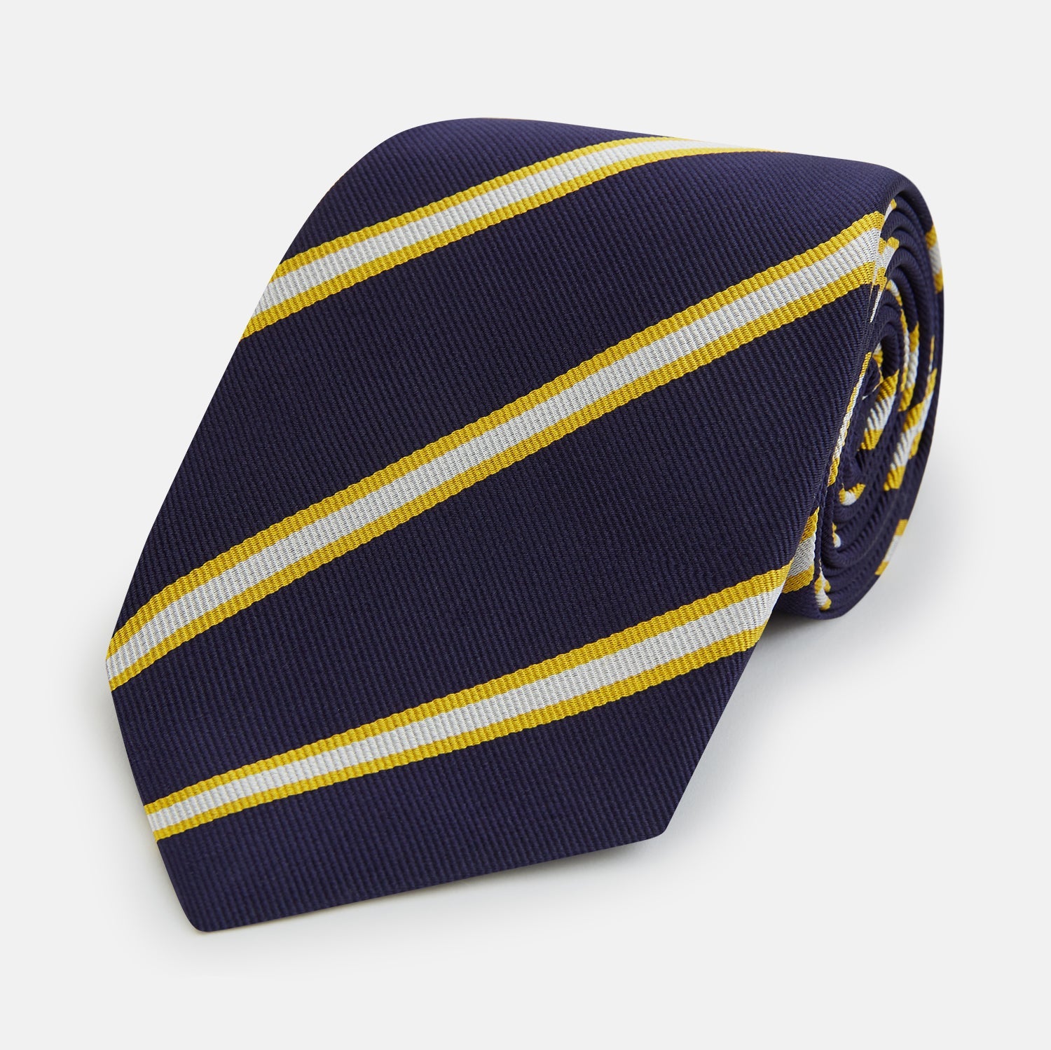 View 1 of product The Turnbull & Asser White and Navy Blazer Silk Tie, featuring diagonal yellow and white stripes, is rolled up neatly on a light gray background.