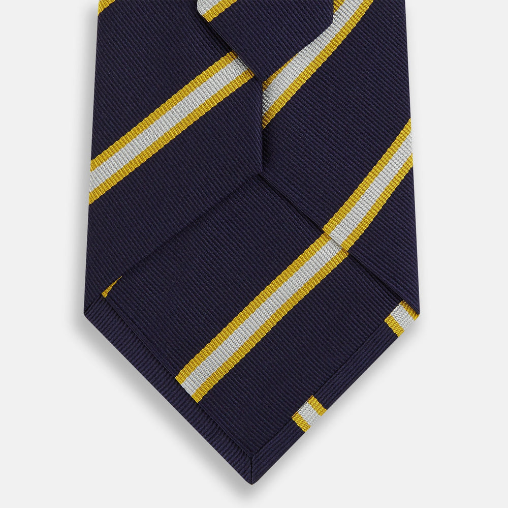 The Turnbull & Asser White and Navy Blazer Silk Tie, featuring diagonal yellow and white stripes, is rolled up neatly on a light gray background.