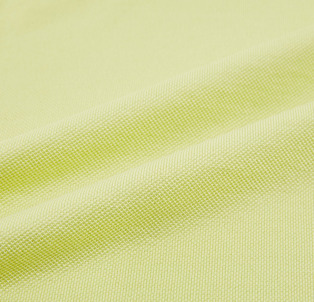 The Turnbull & Asser Lime Green Polo Shirt features a cotton jersey build, short sleeves, a collar, three brown buttons on the placket, and a chest pocket with a button. Shirt shown laid flat on a white background.