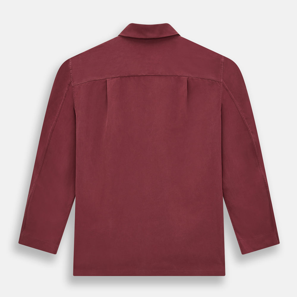 The Turnbull & Asser Burgundy Silk Pyjama Set features a long-sleeve, button-up shirt with chest pocket and matching pants with elastic waistband and side pocket, shown on a white background.