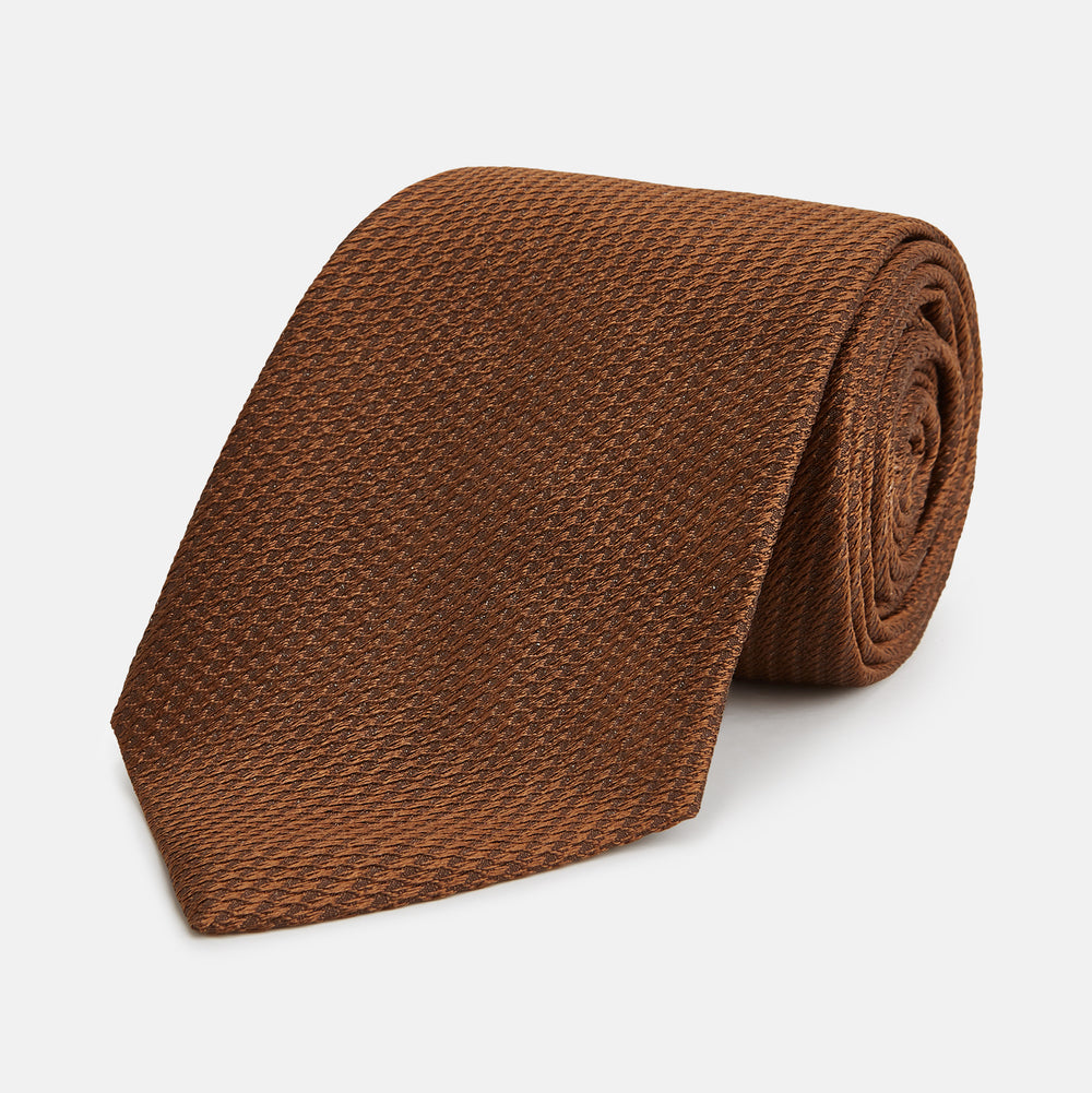The Turnbull & Asser Plain Lace Jacquard Earth Tie, an essential brown wardrobe accessory, is shown rolled up against a plain white background.