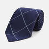 View 1 of product The Turnbull & Asser WINDOW PANE NAVY RIVER TIE features a navy blue base with a subtle light blue check pattern, elegantly rolled on a white background—a sophisticated men's accessory for any wardrobe.