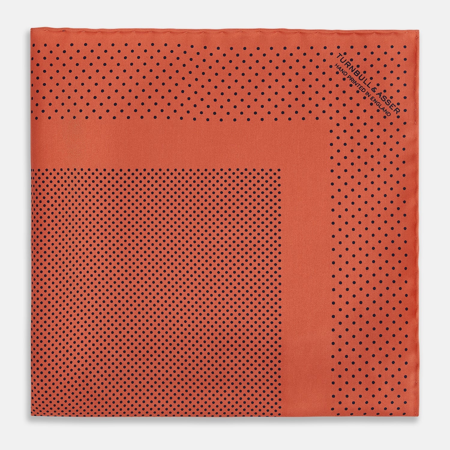 View 3 of product The Orange Dot Silk Pocket Square by Turnbull & Asser is handmade in England from silk, featuring small black polka dots and a solid orange border with a folded corner.