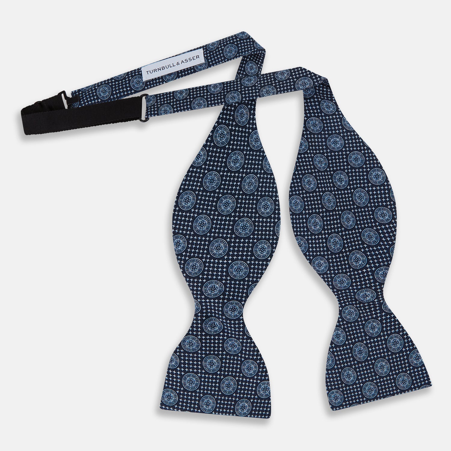 View 2 of product The Navy Medallion Silk Bow Tie by Turnbull & Asser features a navy blue base with light blue geometric grid and medallion motifs, making this sophisticated accessory stand out elegantly against a white shirt.