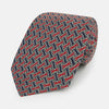 View 1 of product The Turnbull & Asser Red and Navy Weave-Patterned Printed Silk Tie features an intricate geometric design in red, blue, and white. Displayed rolled-up against a plain white background, this classic tie is crafted from luxurious silk.