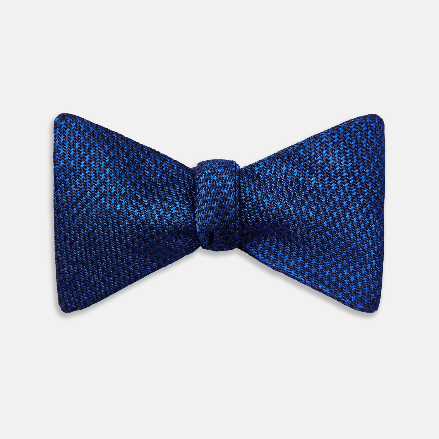 View 1 of product The HOUNDSTOOTH NAVY CRUISE BOW TIE by Turnbull & Asser features a refined textured pattern in blue, neatly tied and set against a white background—a stylish, versatile accessory for the modern gentleman.