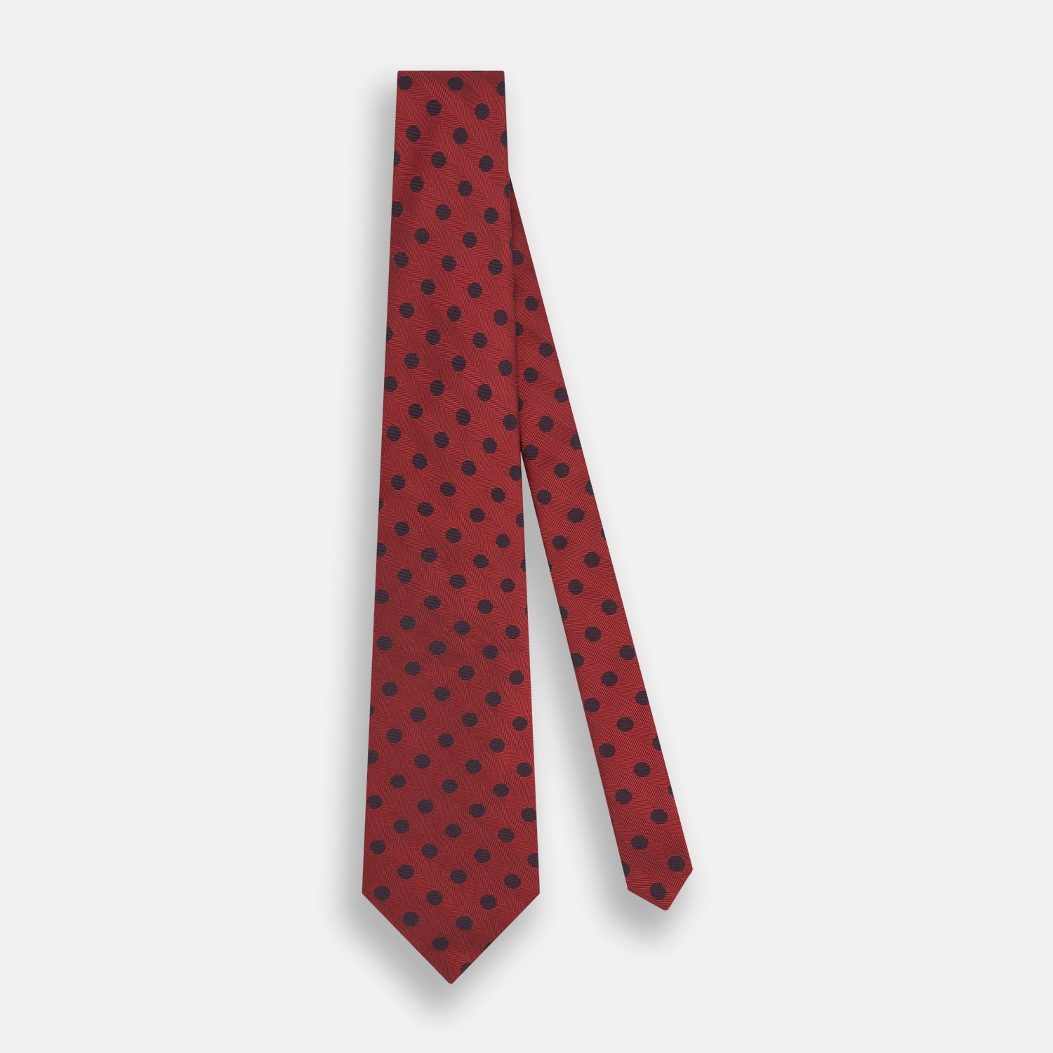 View 2 of product A Turnbull & Asser Navy Dot and Red Silk Tie, featuring a diagonal herringbone pattern with evenly spaced navy blue polka dots, is rolled up on a white background.
