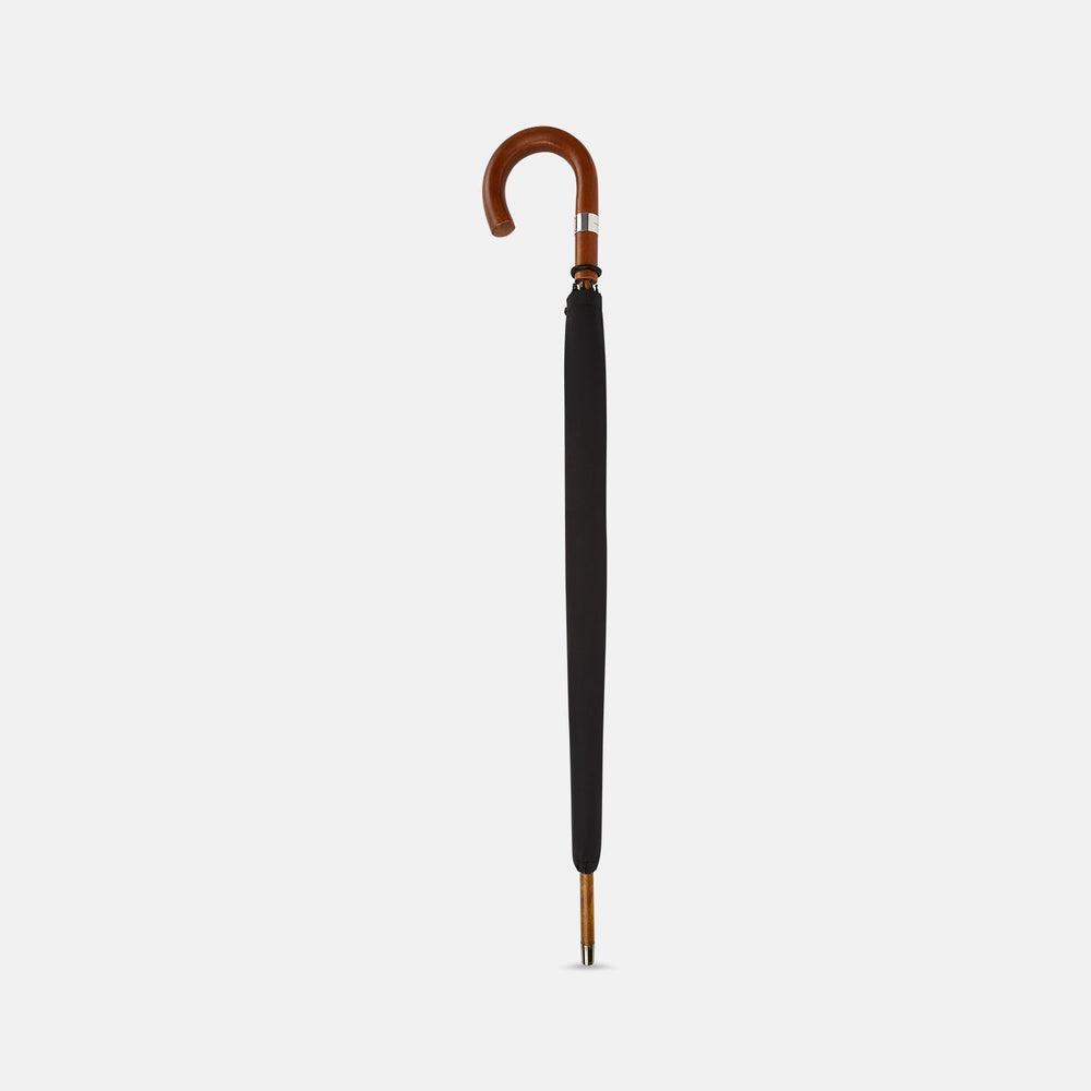 The Turnbull & Asser Black Traveller Umbrella features a Malacca crook handle and straight wooden shaft—a timeless accessory displayed fully opened against a white background.