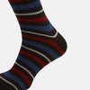 View 4 of product The Turnbull & Asser Dark Chocolate Striped Merino Wool Long Socks are knee-high, featuring horizontal black, red, blue, and gray stripes on a white background.