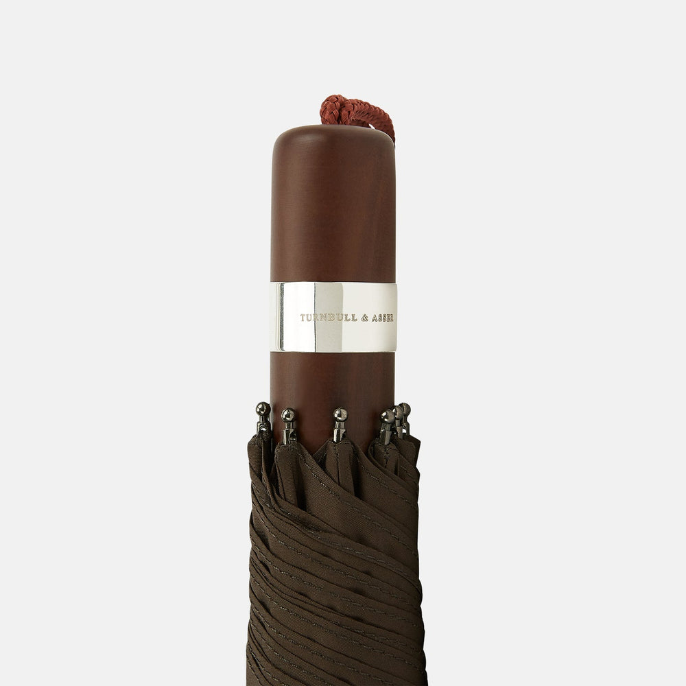 The Turnbull & Asser Brown Telescopic Umbrella features a brown maple handle and silver metal shaft—an elegant choice for men.