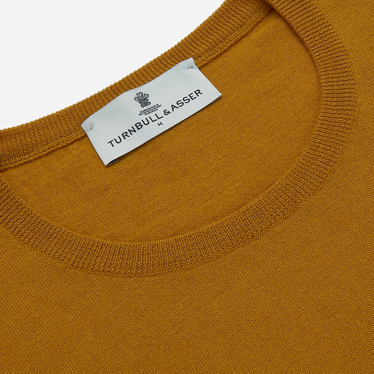 View 2 of product The Turnbull & Asser Gold Crew Neck Merino Jumper, featuring long sleeves and ribbed cuffs and hem, is displayed flat on a white background.