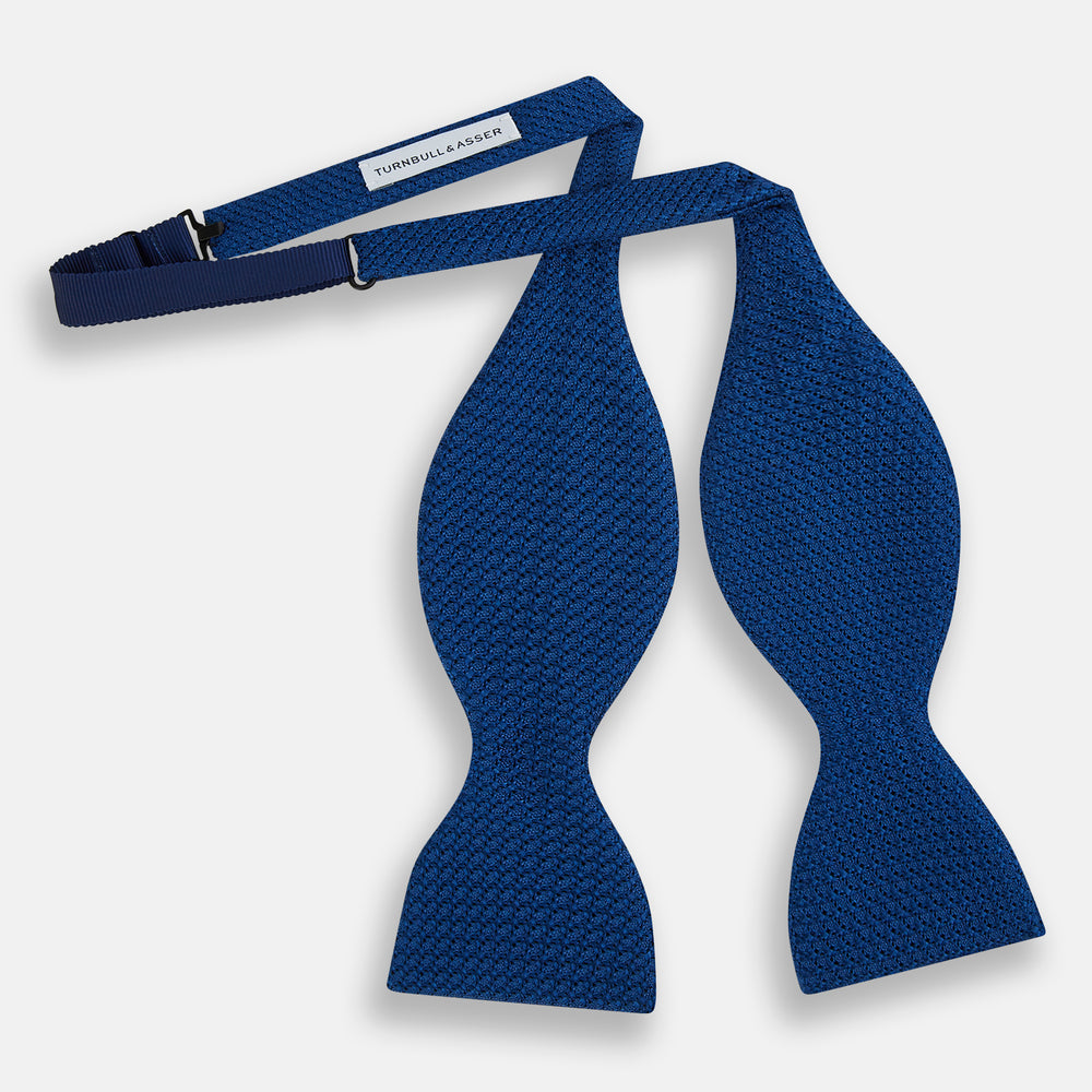 The Turnbull & Asser Azzurro Grenadine Silk Bow Tie, featuring a subtle circular pattern, is crafted from premium silk and shown on a plain white background—a refined accessory for elegant style.