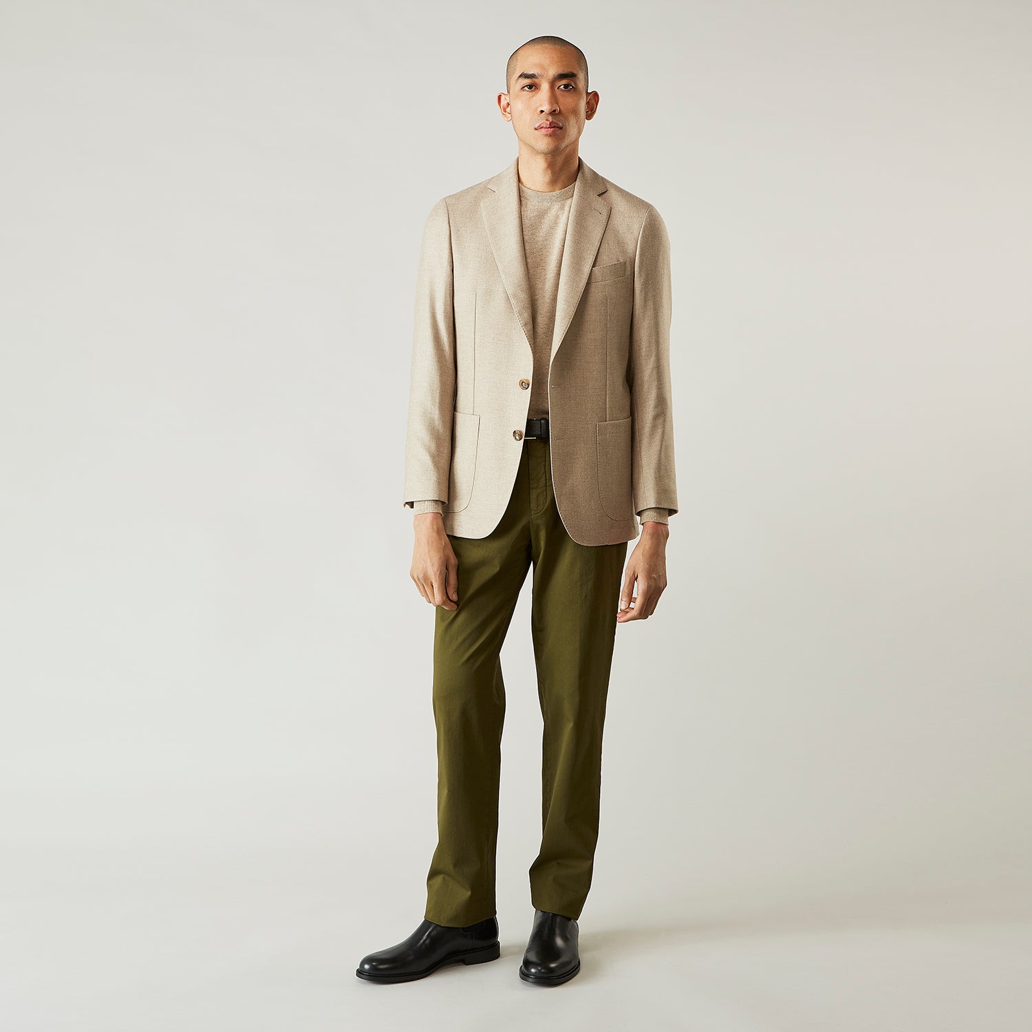 View 3 of product A man wearing the Beige Wool, Silk and Cashmere Bern Jacket by Turnbull & Asser over a matching shirt and olive green pants stands against a plain light gray background, looking to his left with a neutral expression.
