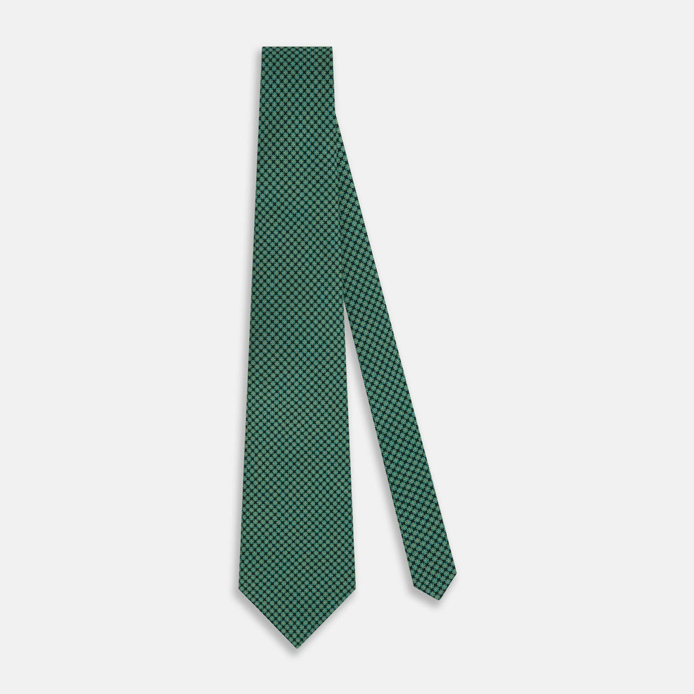 The Forest Green Geometric Floral Printed Silk Tie by Turnbull & Asser is shown rolled up on a white background, its English silk material featuring an elegant green and turquoise pattern.