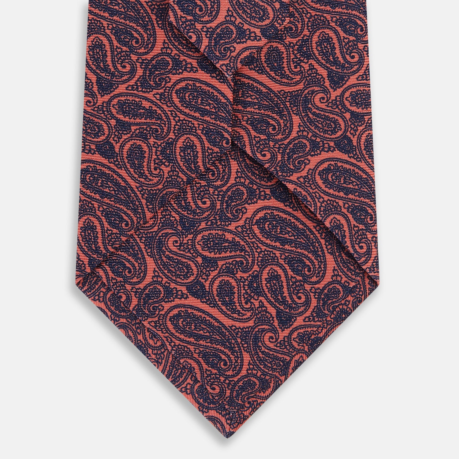 View 3 of product The Turnbull & Asser Orange Paisley Silk Tie, crafted from fine English silk, features an elegant paisley pattern and is stylishly rolled up on a plain white background.