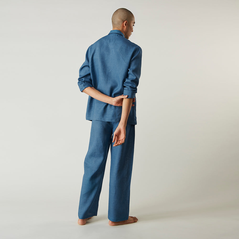 A person stands barefoot against a plain background, wearing the Teal Linen Modern Pyjama Set from Turnbull & Asser.