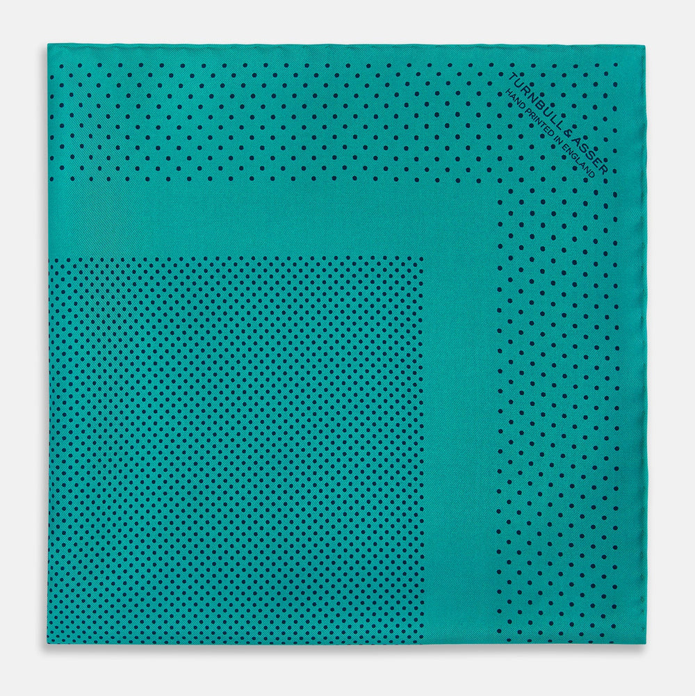 The Turnbull & Asser Petrol Green Dot Silk Pocket Square, made in England, features a border and small black polka dots, neatly folded to showcase both front and back sides.