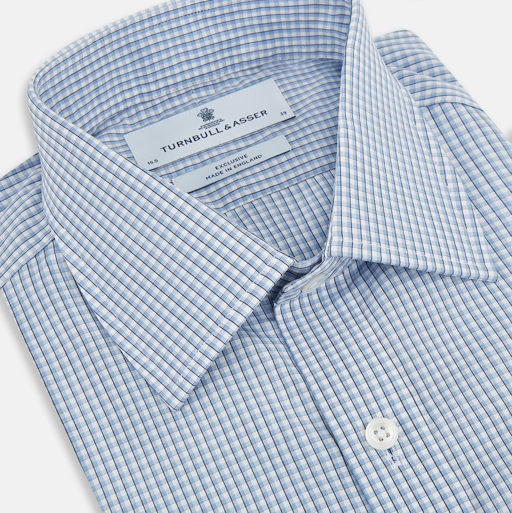 The Turnbull & Asser Blue Micro Shadow Check Mayfair Shirt features a long-sleeve, button-up design with a small blue and white check pattern, pointed T&A collar, and classic cuffs.