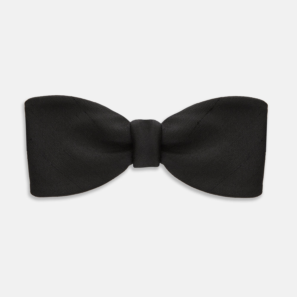 The Casino Royale Bow Tie by Turnbull & Asser, as seen on James Bond, is a classic black Shantung silk bow tie with a smooth, slightly shiny finish, shown against a plain white background.