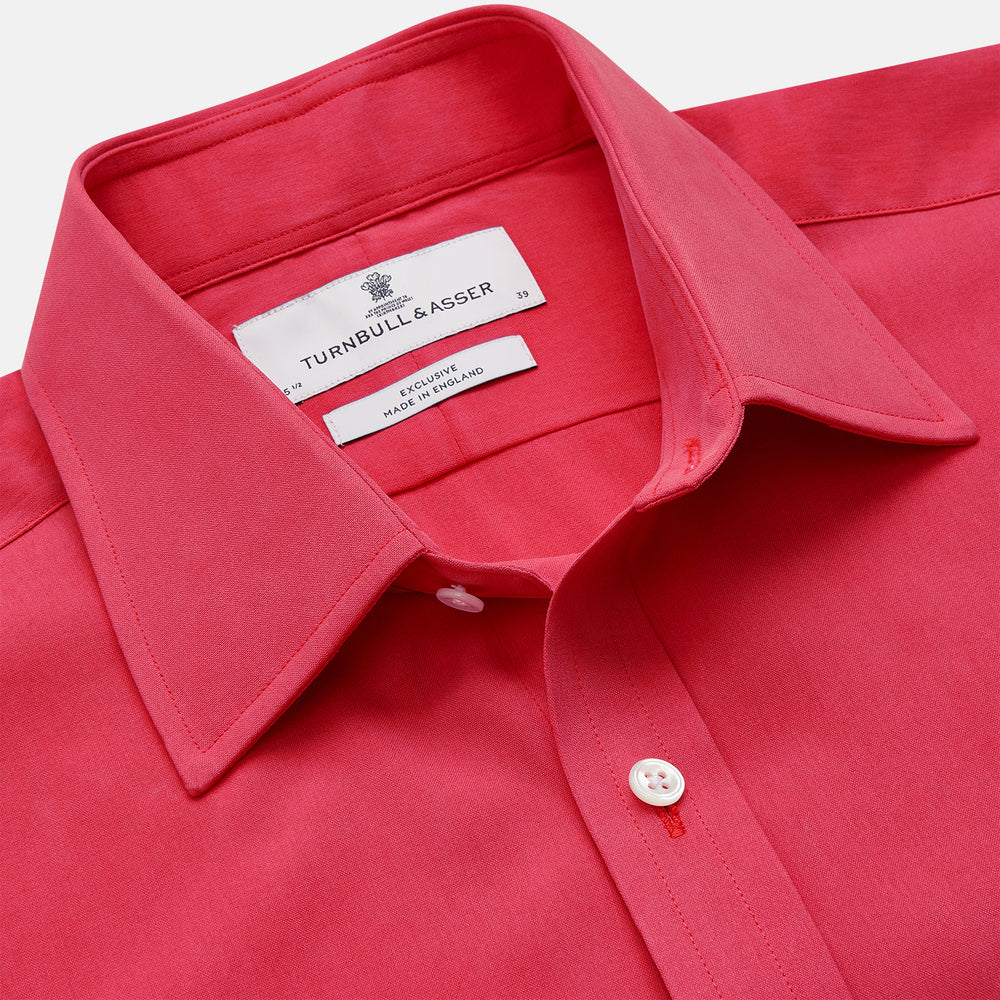 The Turnbull & Asser Coral Pink Silk Regular Fit Mayfair Shirt features long sleeves, a classic collar, and white buttons, displayed laid flat on a plain white background.