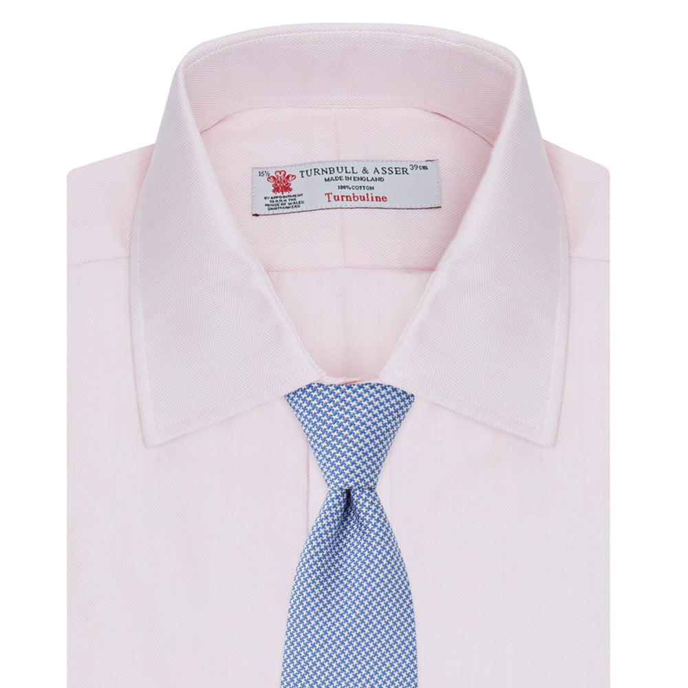 A Pink Herringbone Superfine Cotton Shirt by Turnbull & Asser, featuring a T&A collar and 3-button cuffs, is neatly folded with the inner collar label visible and white buttons, set against a plain white background.