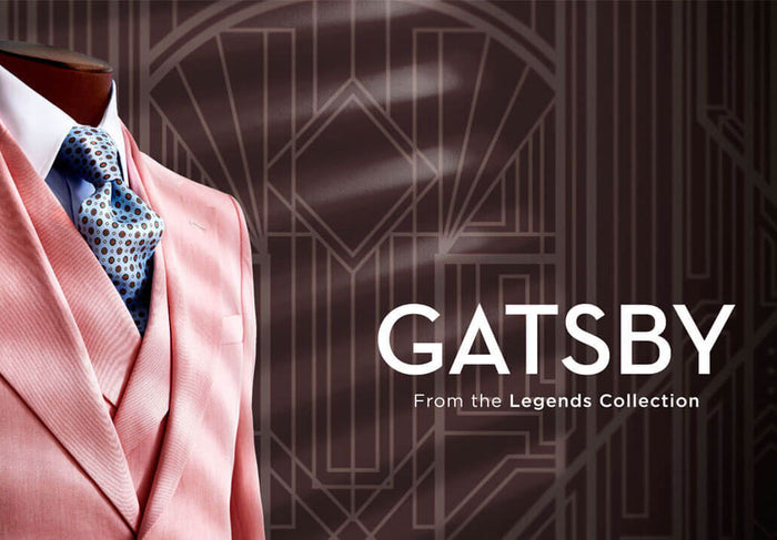 A mannequin dressed in a pink pinstripe suit, white shirt, and patterned blue tie is shown beside the text GATSBY From the Legends Collection on a geometric, art deco background.