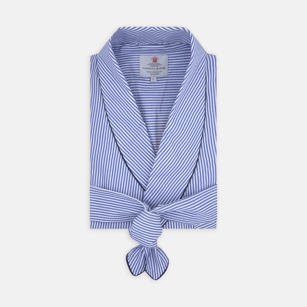 The Turnbull & Asser Blue Bengal Stripe Piped Cotton Gown, featuring a shawl collar and belt, is elegantly folded and displayed on a white background.