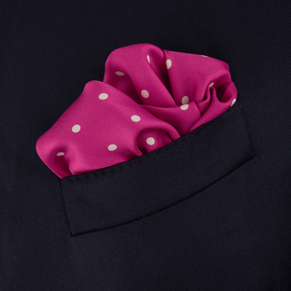 The Fuchsia Spot Silk Pocket Square by Turnbull & Asser features bright fuchsia silk with evenly spaced white spots and the brand’s name in one corner. A classic accessory, it is shown with one corner folded over.