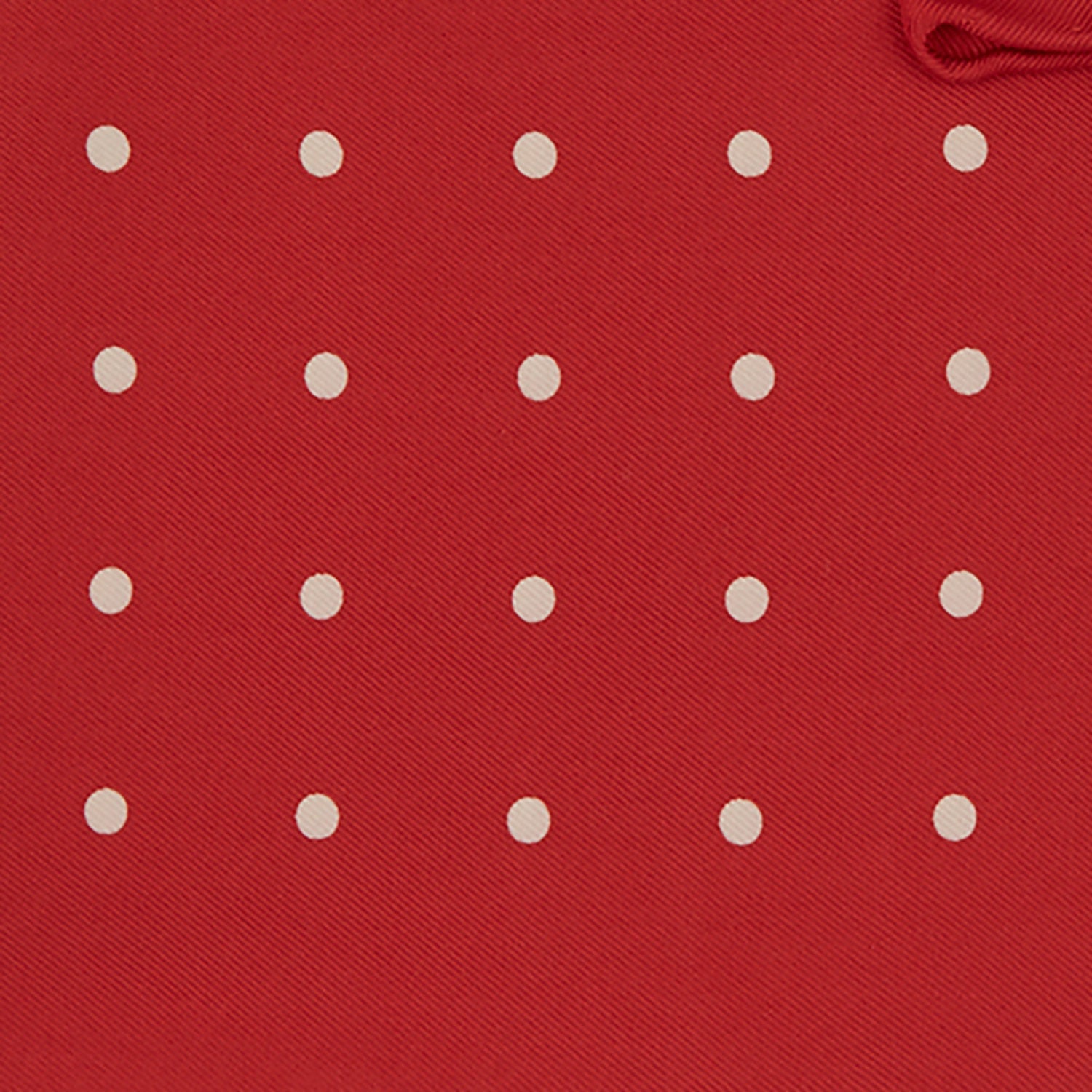 View 3 of product The Red and White Spot Silk Pocket Square by Turnbull & Asser features evenly spaced white polka dots on red silk with the brand's name printed in one corner. A folded edge reveals the reverse of this timeless pocket square.
