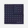 View 1 of product The Navy Spot Silk Pocket Square by Turnbull & Asser features a white polka dot pattern and is neatly folded at one corner, with the brand name printed in white on the lower right—perfect for pairing with pinstripe suits.