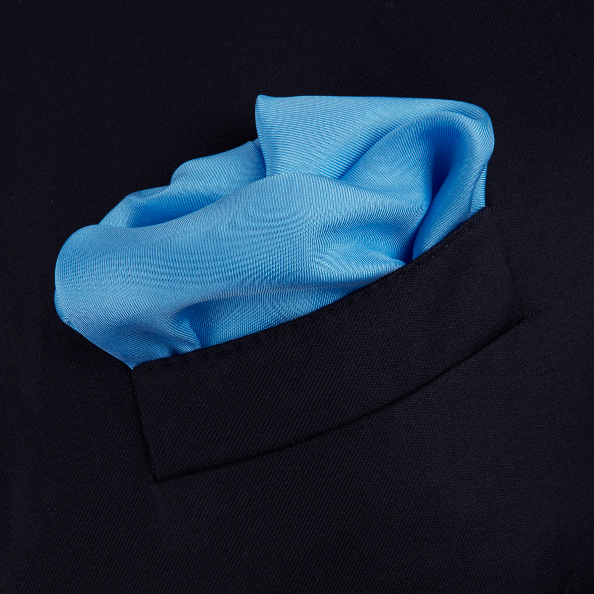 View 4 of product A Blue and White Piped Silk Pocket Square by Turnbull & Asser, neatly folded with the brand name in white on the lower right corner, displayed against a plain white background.