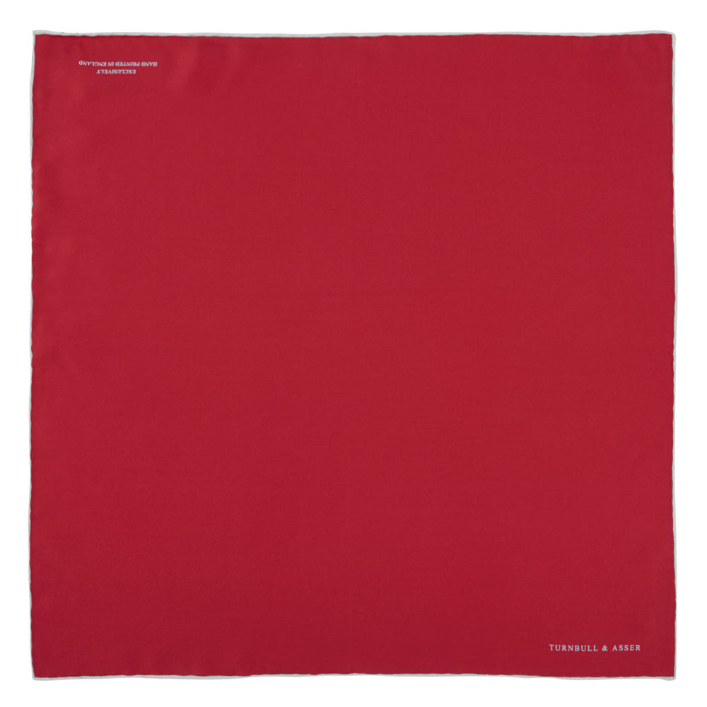 A classic accessory, the Turnbull & Asser Red and White Piped Silk Pocket Square is neatly folded to showcase both colors, with the brand’s logo in white on the corner.