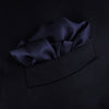 View 4 of product The Navy and White Piped Silk Pocket Square by Turnbull & Asser features white edging and partial corner folding, with the brand’s name printed in white near the lower edge.