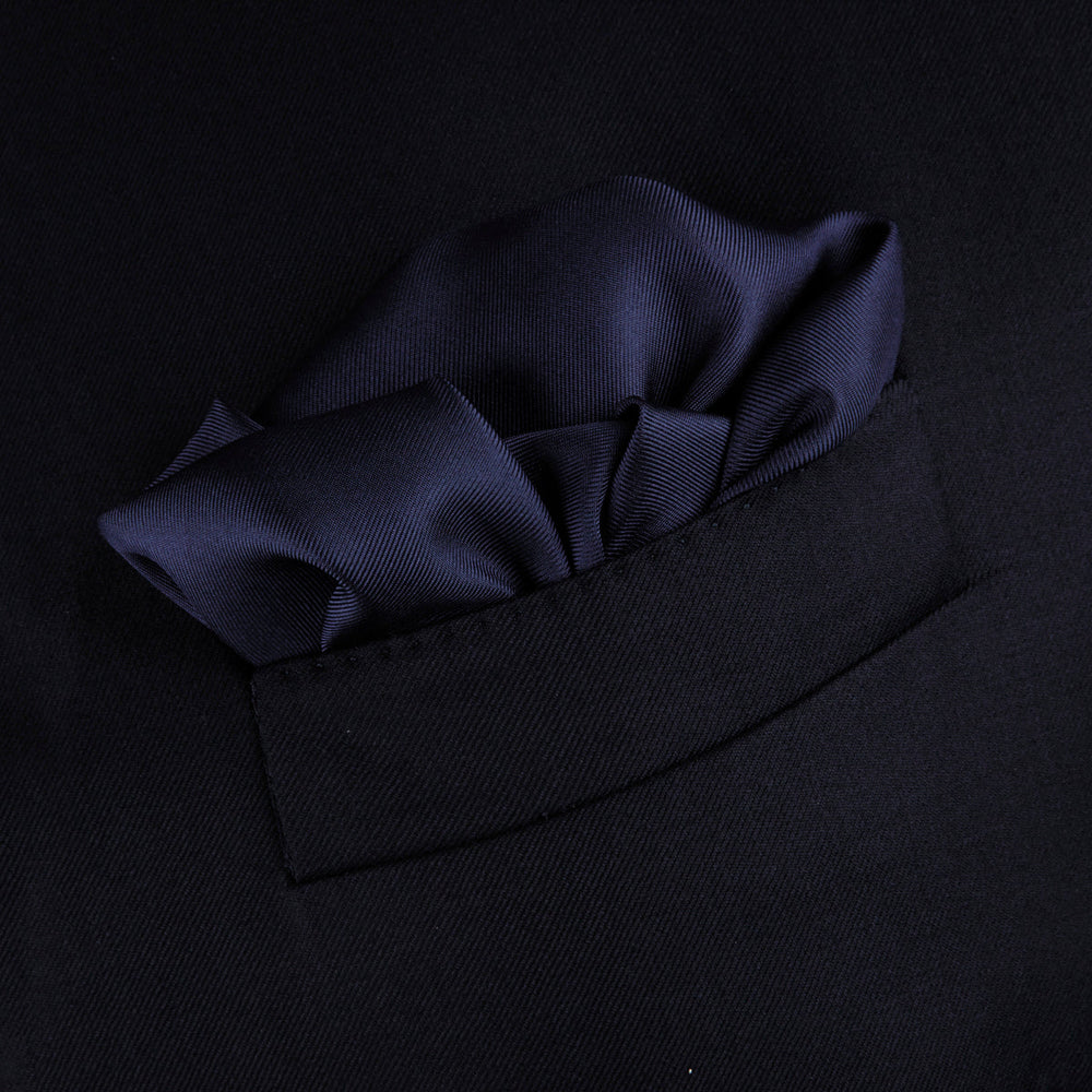 The Navy and White Piped Silk Pocket Square by Turnbull & Asser features white edging and partial corner folding, with the brand’s name printed in white near the lower edge.