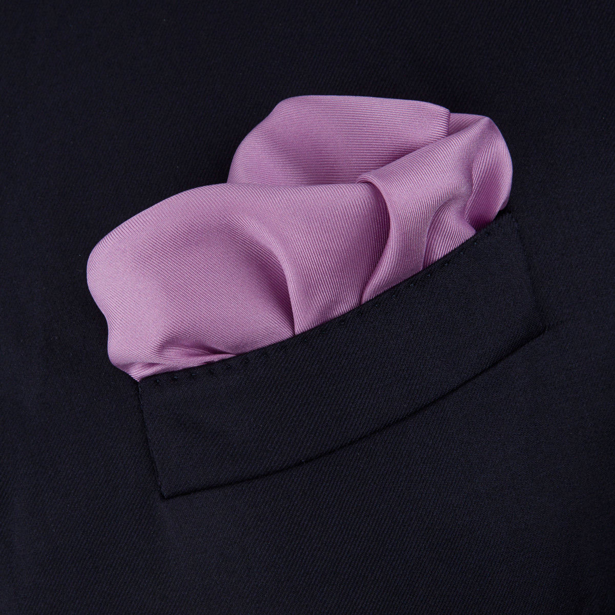 View 4 of product The Lilac and Navy Piped Silk Pocket Square by Turnbull & Asser features a folded lilac design with dark blue trim and the brand's name printed in white in the lower right corner.