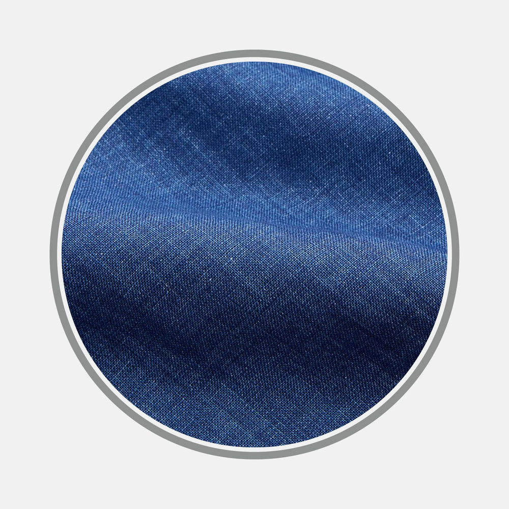 Close-up of BESPOKE FABRIC 0017 05 by Turnbull & Asser—blue denim fabric with visible weave texture and subtle diagonal lines, framed in a circular border on a white background.