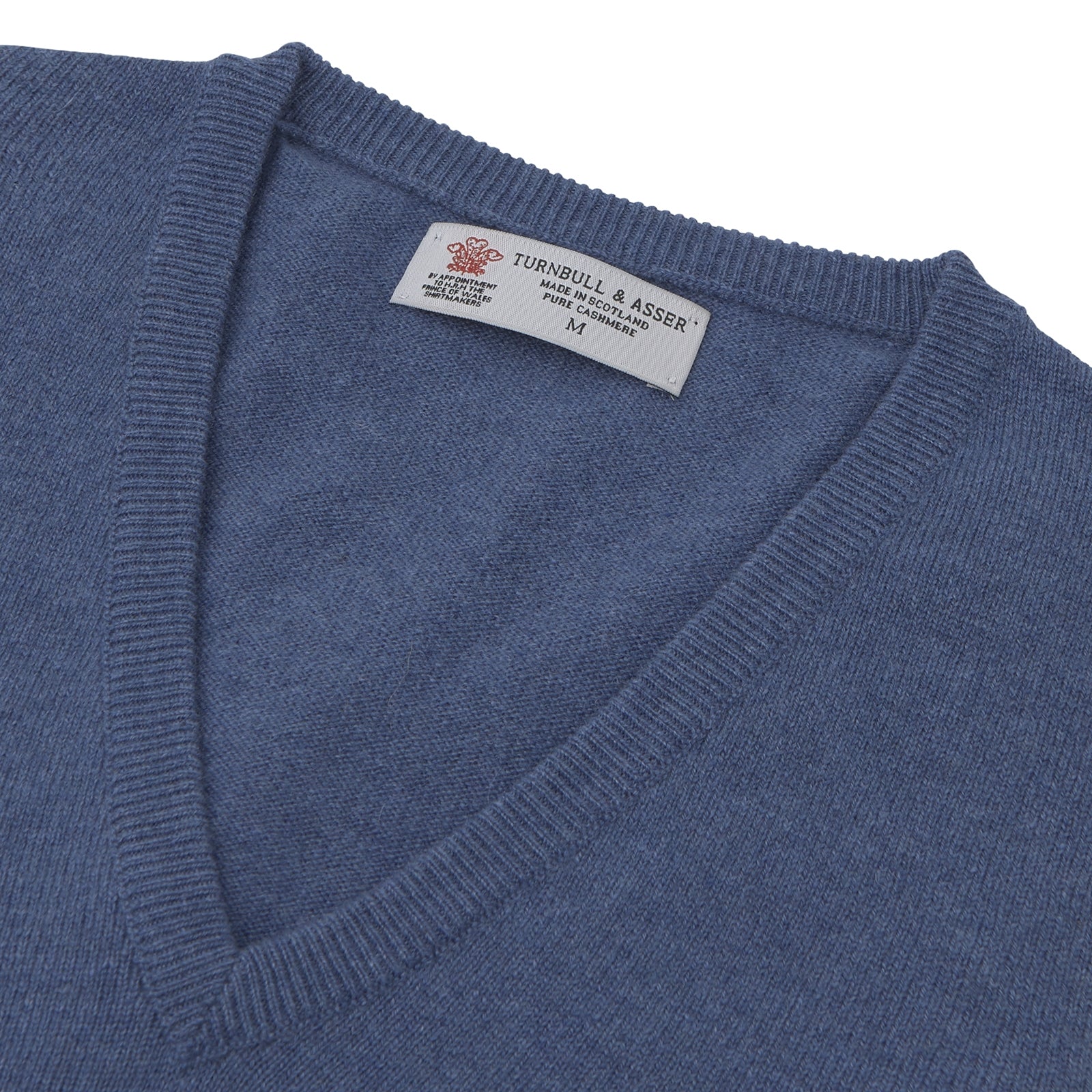 View 2 of product The Turnbull & Asser Blue V-Neck Cashmere Slipover, neatly folded with the label visible, is crafted from soft cashmere and ideal for formal layering. Shown against a white background.